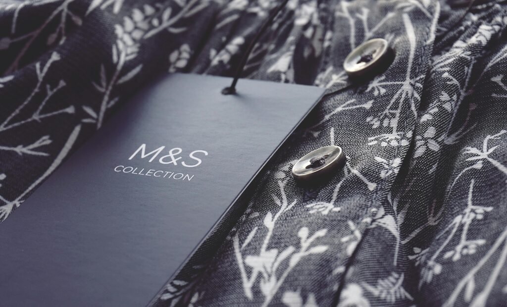 Close-up of black and white floral fabric with buttons and label, featuring elegant design.